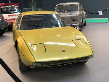 Gele vintage sportwagen tentoongesteld op het Antwerp Classic Salon 2020 met een andere klassieke auto op de achtergrond.