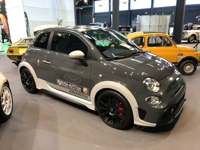Een grijze Abarth-auto tentoongesteld op de autoshow Antwerp Classic Salon 2020 met andere oldtimers op de achtergrond.