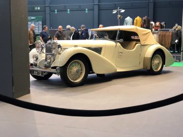 Vintage crèmekleurige cabriolet tentoongesteld op de tentoonstelling Antwerp Classic Salon 2020 met toeschouwers op de achtergrond.