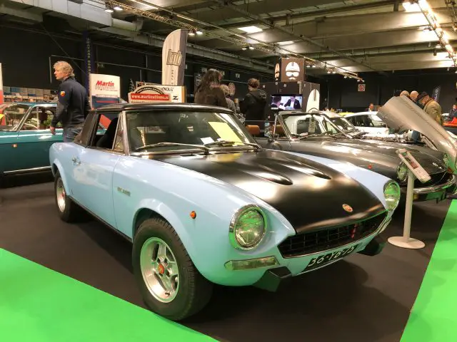 Blauwe vintage sportwagen te zien op het Antwerp Classic Salon 2020 met deelnemers op de achtergrond.