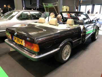 Een klassieke BMW-cabriolet tentoongesteld op de indoortentoonstelling Antwerp Classic Salon 2020 met bezoekers op de achtergrond.
