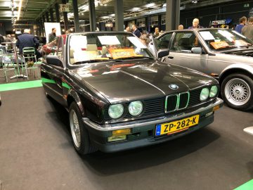 Een klassieke zwarte BMW-auto te zien op het Antwerp Classic Salon 2020 met mensen op de achtergrond.
