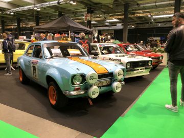 Een oldtimershow op het Antwerp Classic Salon 2020 met klassieke racewagens en toeschouwers in zicht.