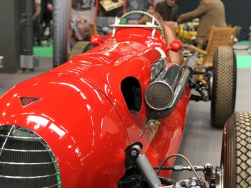 Rode vintage raceauto tentoongesteld op Antwerp Classic Salon 2020 met zichtbare motor en spaakwielen.