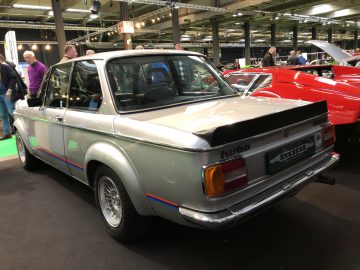 Zilveren vintage turbosportwagen te zien op het Antwerp Classic Salon 2020 met toeschouwers op de achtergrond.