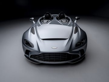 Zilveren Aston Martin V12 Speedster met open ontwerp op een grijze achtergrond.