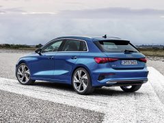 Blauwe Audi A3 Sportback geparkeerd aan de kant van een weg met een bewolkte lucht op de achtergrond.