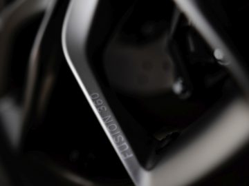 Close-up van een stuurwiel en dashboardbediening met BAC Mono-merklogo's wazig op de achtergrond.