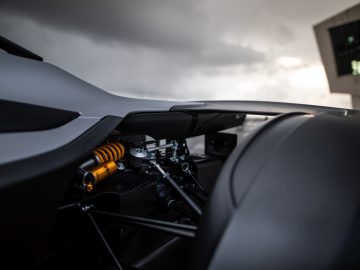 Close-up van de achterwielophanging van een BAC Mono-sportwagen onder donkere wolken.