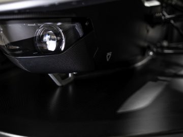 Close-up van een BAC Mono koolstofvezel gedetailleerde sportwagenkoplamp en frontsplitter.