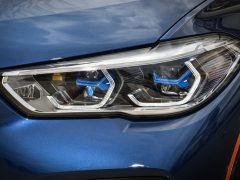 Een close-up van de led-koplamp van een moderne auto op een glanzende blauwe carrosserie tijdens een quiz.
