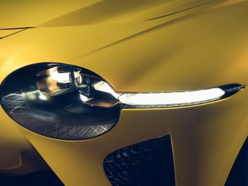 Close-up van het koplamp- en grille-ontwerp van een moderne Bentley Mulliner Bacalar met een gele verfafwerking.
