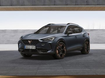 Een moderne crossover-SUV Cupra Formentor geparkeerd voor een minimalistisch gebouw met een betonnen gevel.