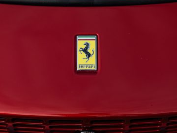 Een close-upfoto van het embleem van een rode Ferrari Roma op de motorkap.