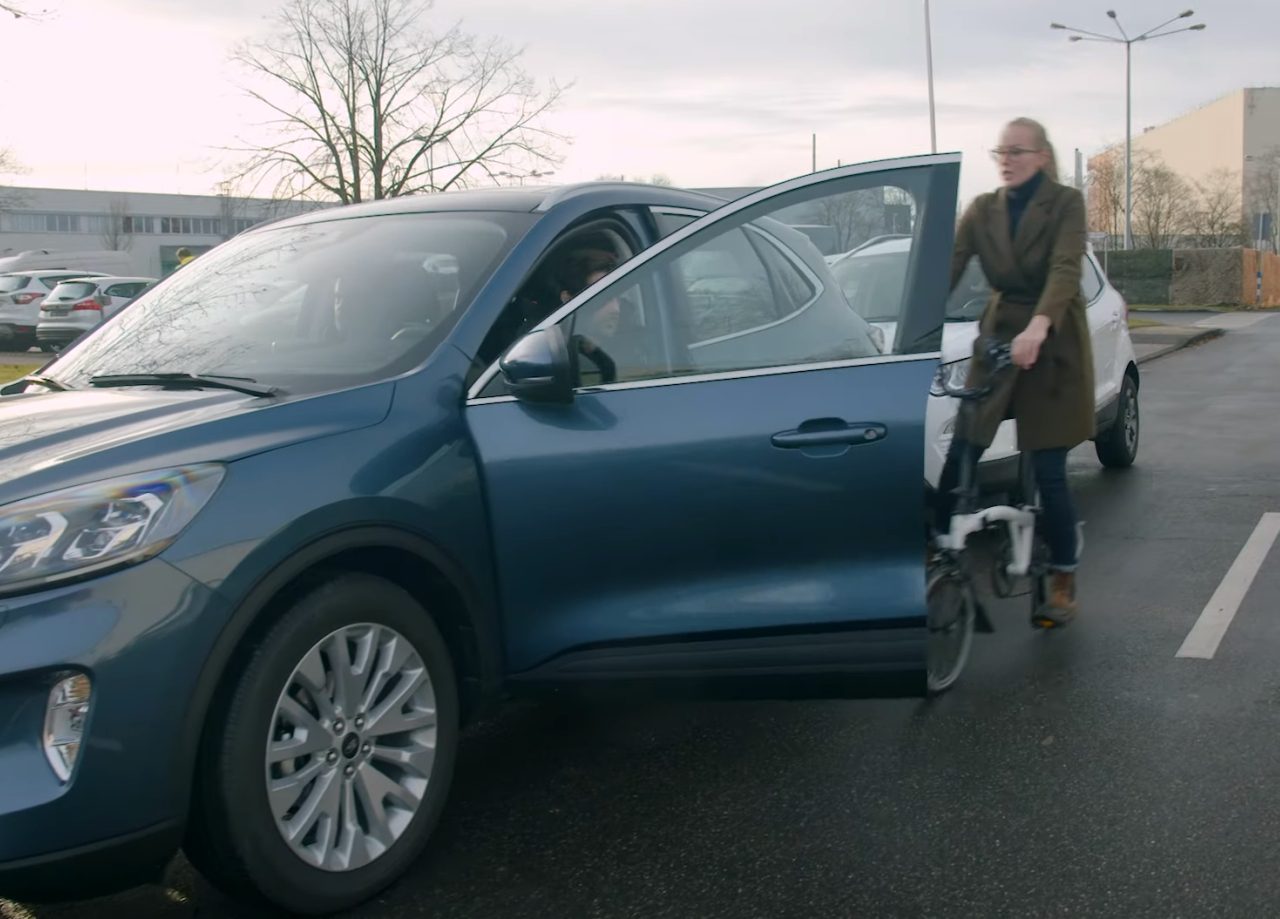 Vrouw verlaat een blauwe Ford-auto op een parkeerplaats.