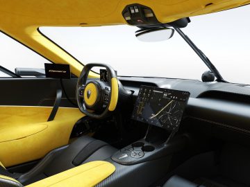 Binnenaanzicht van een moderne Koenigsegg Gemera met gele accenten en een digitaal dashboard.