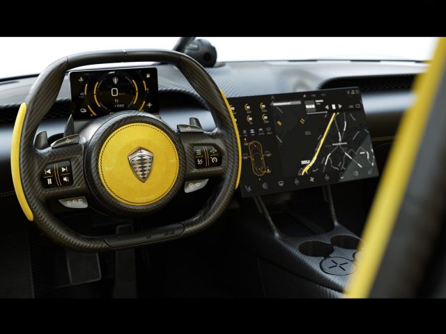Modern Koenigsegg Gemera-interieur gericht op een stuur met een geel logo en digitale dashboarddisplays.