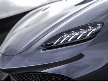 Close-up van de koplamp en grille van een Koenigsegg Gemera met een focus op design en aerodynamica.