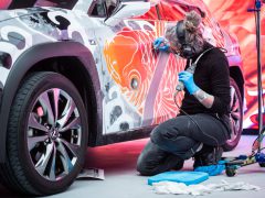 Kunstenaar die een kleurrijk ontwerp toepast op de buitenkant van een Lexus UX.