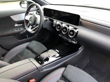 Binnenaanzicht van een Mercedes-Benz CLA met een lederen dashboard met ronde ventilatieopeningen, een multifunctioneel stuur en een middenconsole met aanraakbediening.