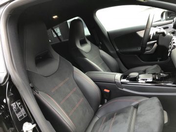 Binnenaanzicht van een Mercedes-Benz CLA met zwart gestoffeerde stoelen met rode stiksels.