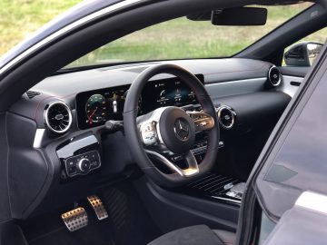 Binnenaanzicht van een Mercedes-Benz CLA-voertuig met het stuur, het digitale dashboard en de middenconsole.