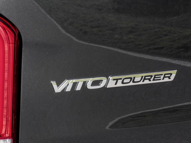 Close-up van het zijpaneel van een Mercedes-Benz Vito met het 'Vito Tourer'-embleem en een deel van het achterlicht.