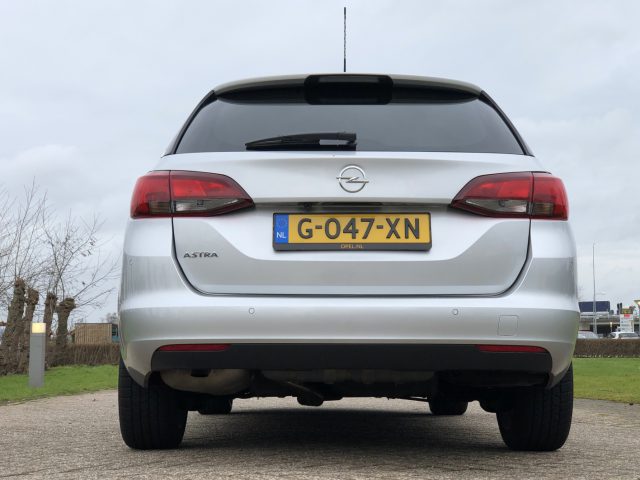 Zilverkleurige Opel Astra Sports Tourer, van achteren gezien.