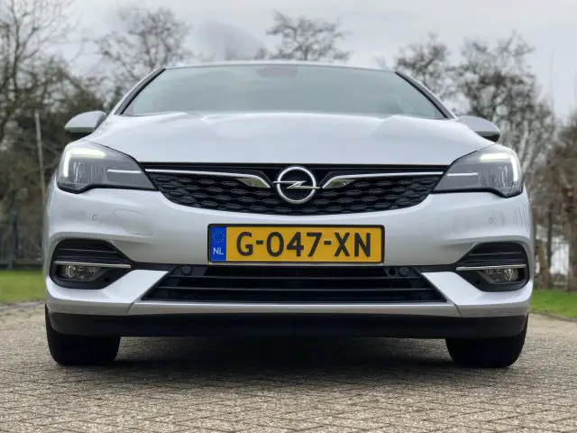 Vooraanzicht van een witte Opel Astra Sports Tourer die buiten geparkeerd staat.
