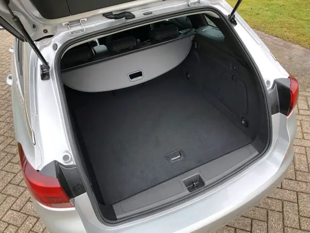 Lege kofferbak van een zilveren Opel Astra Sports Tourer, van achteren gezien met open kofferdeksel.