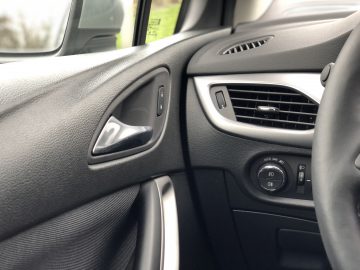 Binnenaanzicht van de Opel Astra Sports Tourer, met de nadruk op de bestuurdersdeur met bedieningselementen voor de ramen en zijspiegels.