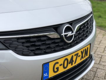 Close-up van de grille en het embleem van een zilveren Opel Astra Sports Tourer, met een Europees kenteken.