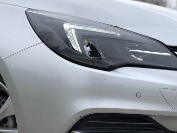 Close-up van de koplamp en het voorwiel van een Opel Astra Sports Tourer.