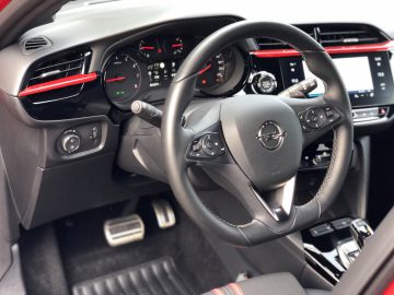 Binnenaanzicht van een modern Opel Corsa-dashboard en stuurwiel met bedieningsknoppen.