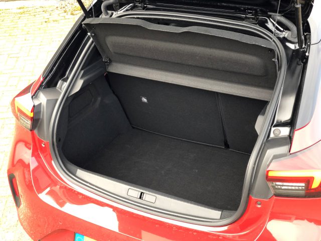 Rode Opel Corsa met een open kofferbak waardoor een schone en lege laadruimte zichtbaar is.