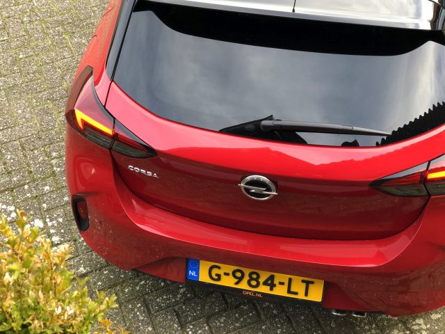 Achteraanzicht van een Opel Corsa geparkeerd in een woonstraat.