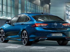 Een blauwe Opel Insignia geparkeerd in een stedelijke omgeving in de schemering.