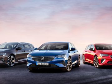 Drie Opel Insignia-auto's naast elkaar tentoongesteld bij zonsondergang.
