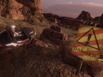 Terreinwagen geparkeerd naast een bord met 'gevaar' in een rotsachtig woestijnlandschap, in de schaduw van een viaduct.
