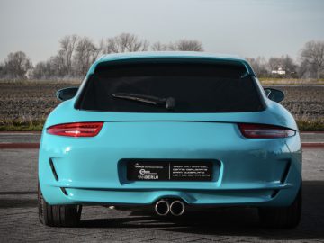 Een blauwe Porsche Boxster Shooting Brake geparkeerd op een asfaltoppervlak met de achterkant naar de camera gericht.