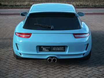 Achteraanzicht van een blauwe Porsche Boxster Shooting Brake geparkeerd op een verhard terrein met dubbele uitlaten en opvallende achterlichten.