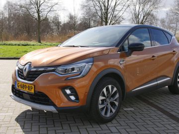Oranje Renault Captur parkeerde buiten op een zonnige dag.