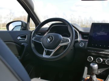 Modern Renault Captur-interieur met een stuur met logo, digitale schermen en een strak dashboardontwerp.
