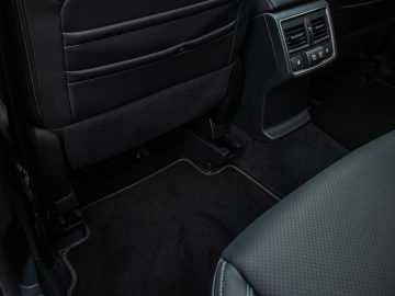 Achterste auto-interieur van de Subaru Forester e-Boxer met zwartleren stoelen, tapijt en centrale ventilatieopeningen voor de klimaatregeling.
