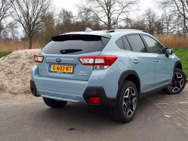 Een blauwe Subaru XV e-Boxer geparkeerd op een grindgebied nabij een grasveld.