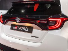 Achteraanzicht van een Toyota GR Yaris met duidelijke achterlichten en badges op een autoshow.