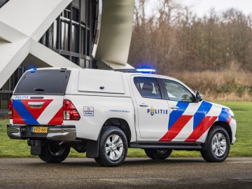 Een Nederlands politievoertuig, een Toyota, met geactiveerde noodverlichting.