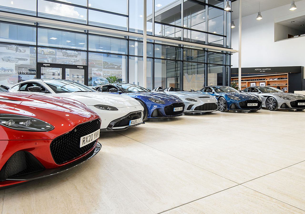 Een reeks luxe sportwagens van Aston Martin tentoongesteld in een ruime showroom.