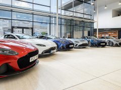 Een reeks luxe sportwagens van Aston Martin tentoongesteld in een ruime showroom.