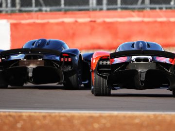 Twee krachtige Aston Martin-auto's racen op een circuit.